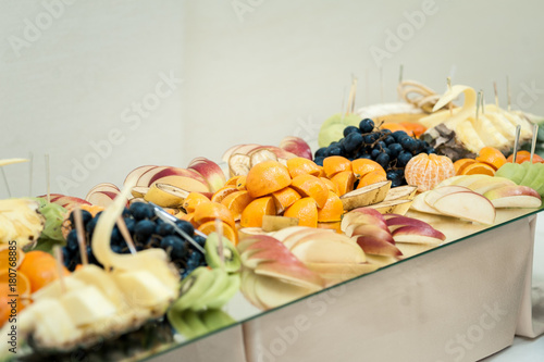 Fresh fruits and berries of different bright colors cut in small pieces are served on a table in restourant photo