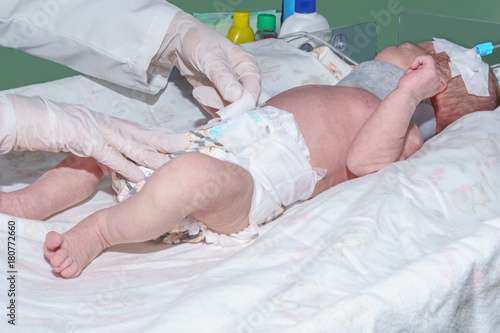 Nurse changing diaper of newborn baby in neonatal intensive care unit at children's hospital photo
