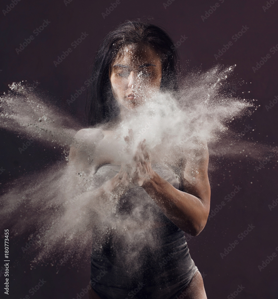 Fototapeta premium Studio portrait of woman dancing with flour