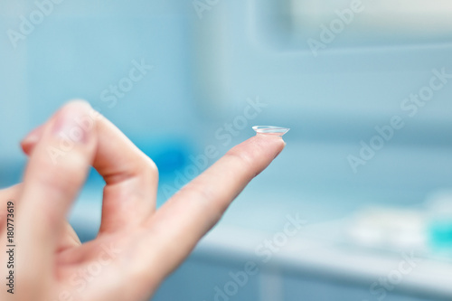 girl holds finger on a contact lens, closeup