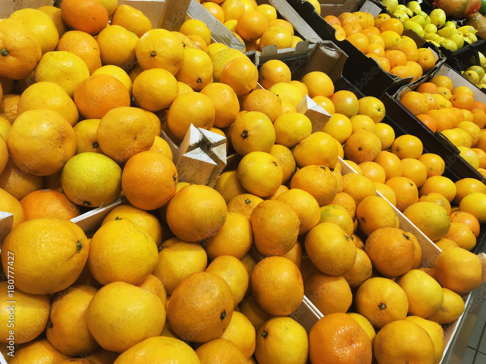 Many orange fresh fruits mandarins lying in boxes in supermarket