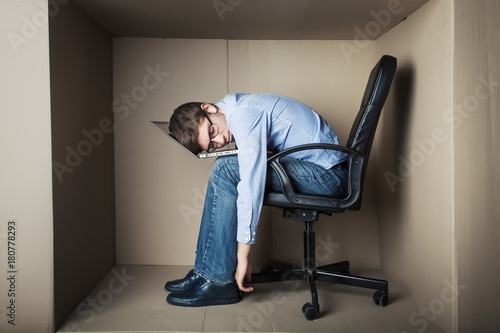 teenager, student in small office working on laptop, in an uncomfortable position, asleep