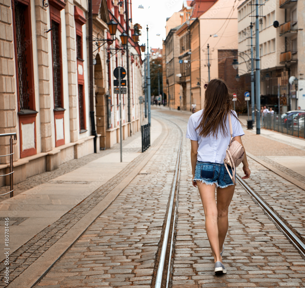 Young brunette woman walking and relaxing in old city street