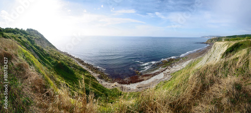 Beautiful view of seashore. Rocks, beach and sea against blue sky.