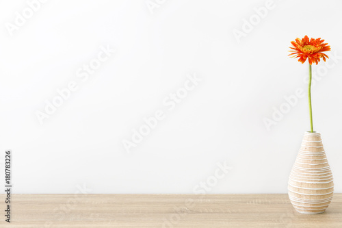 Modern vase with Gerbera flower and beautiful orange  yellow on wood table and white wall background.