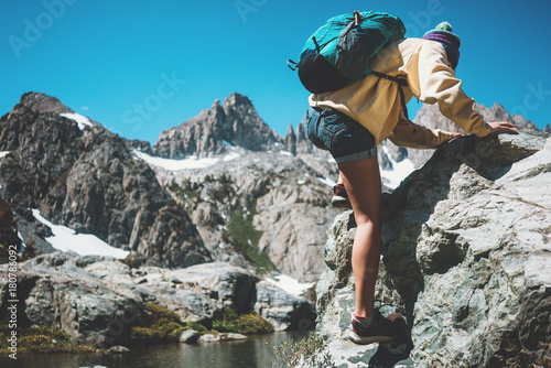 Active traveler woman backpacker rock climbing and looking at stunning mountain wild beauty
