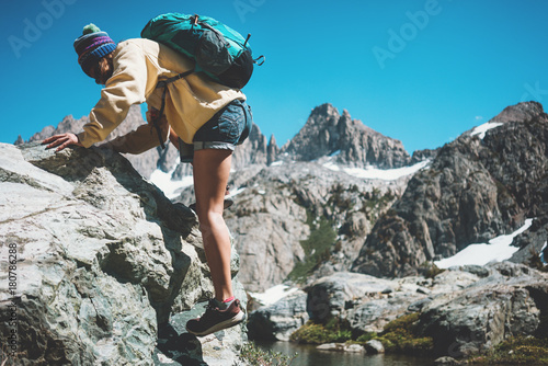 Active traveler woman backpacker rock climbing and looking at stunning mountain wild landscape