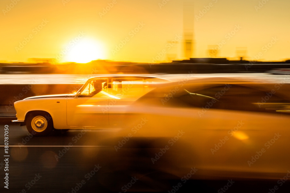Fototapeta premium Moving cars on sunset / Two moving cars on background of setting sun in Saint Petersburg, Russia. 