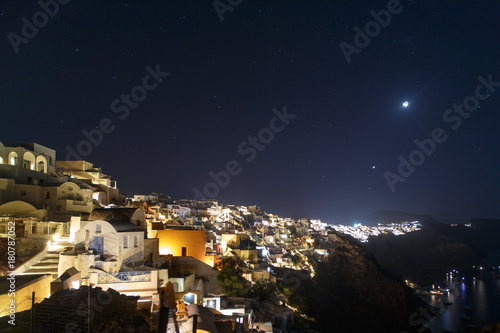 Oia town on Santorini island, Greece at night. Traditional and famous houses and churches with blue domes over the Caldera, Aegean sea © Sokirlov
