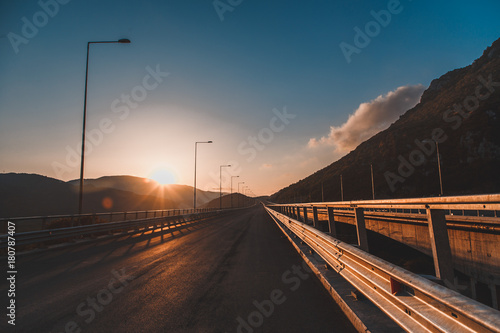 Beautiful asphalt road. Colorful landscape with high rocks, mountain road with a perfect asphalt, trees and amazing sunny cloudy sky at sunset in summer. Travel background. Highway at mountains. Road photo