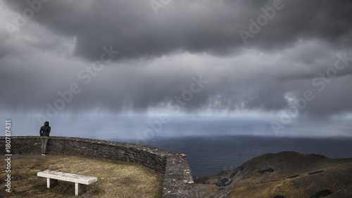 Mujer asomada al mirador de Vixía Herbeira ve acercarse la tormenta,  Costa ártabra, cerca de san Andrés, Galicia, españa photo