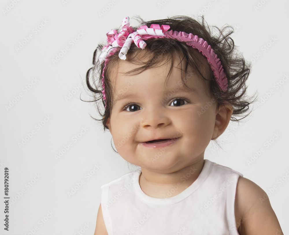 Smiling, mixed race, baby girl wearing pink headband on white background Smiling, mixed race, baby girl wearing pink headband on white background