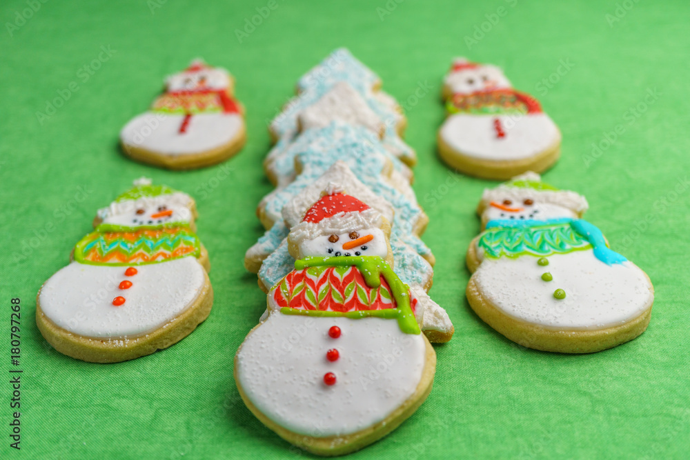 Christmas snowman and tree cookies on green background.