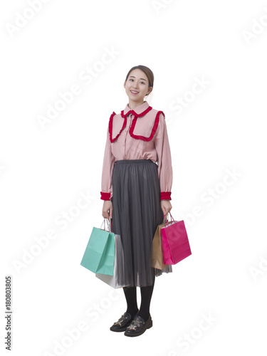 Full body portrait of happy young Asian woman holding shopping bags on white background