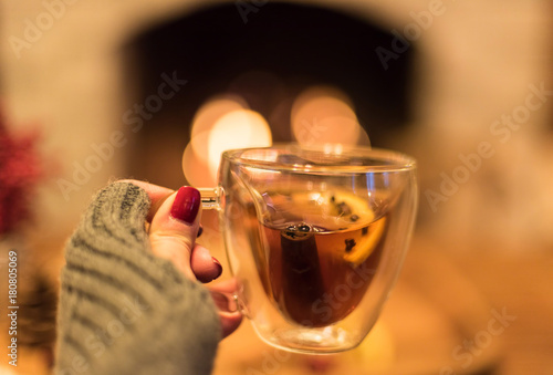 Closeup of a woman's hand holding a warm winter beverage in front of the fire photo