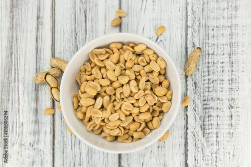 Wooden table with salted and roasted peanuts (close-up shot)