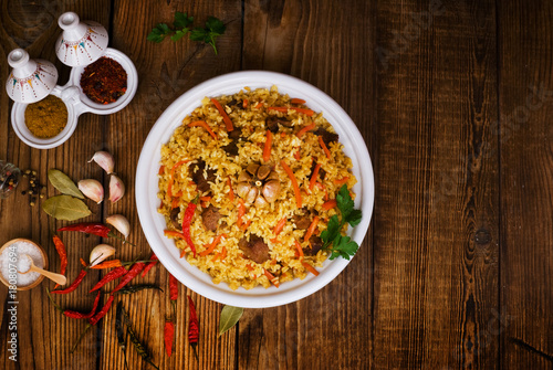 pilaf in a plate on wooden background, top view