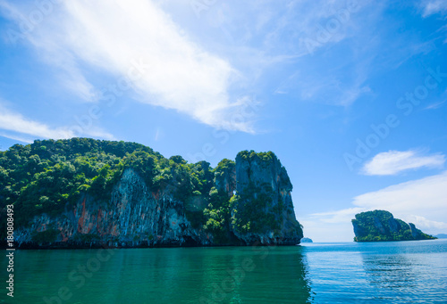 LIMESTONE ISLAND IN ANDAMAN SEA OF THAILAND , BLUE SKY CLOUD SUNNY DAY IN BACKGROUND