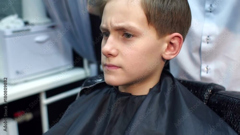 Close-up of the face of a young guy in a hairdresser. The hairdresser makes a stylish hairstyle for a teenager. Close-up of the face of a young guy in a hairdresser. The hairdresser makes a stylish hairstyle for a teenager.