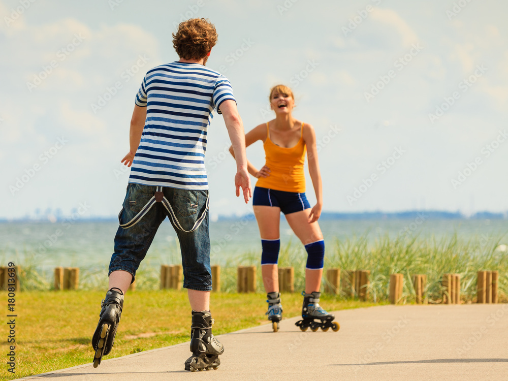Fototapeta premium Young couple on roller skates riding outdoors