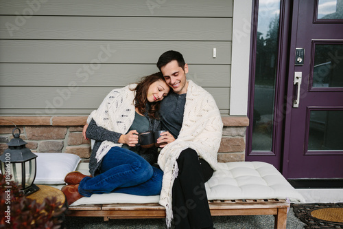 Couple in love sitting on front porch drinking coffee