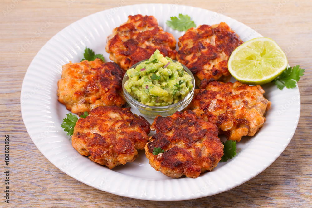 Salmon patties or cakes, lime and avocado on white plate. Fritters of fish. Salmon burgers. Healthy snack or take-away lunch bites Salmon patties or cakes, lime and avocado on white plate. Fritters of fish. Salmon burgers. Healthy snack or take-away lunch bites