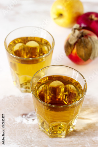Apple juice in glasses and fresh apples on a wooden background. Rustic style.
