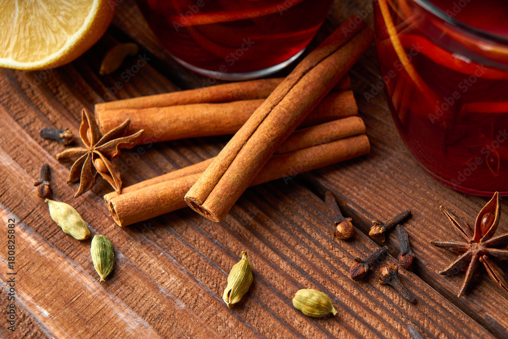 Autumn warming drink. Hot mulled wine, with lemon, anise, cinnamon, cloves, cardamom. Autumn dark still life. Mulled wine with slice of lemon and spices. Autumn warming drink. Hot mulled wine, with lemon, anise, cinnamon, cloves, cardamom. Autumn dark still life. Mulled wine with slice of lemon and spices.