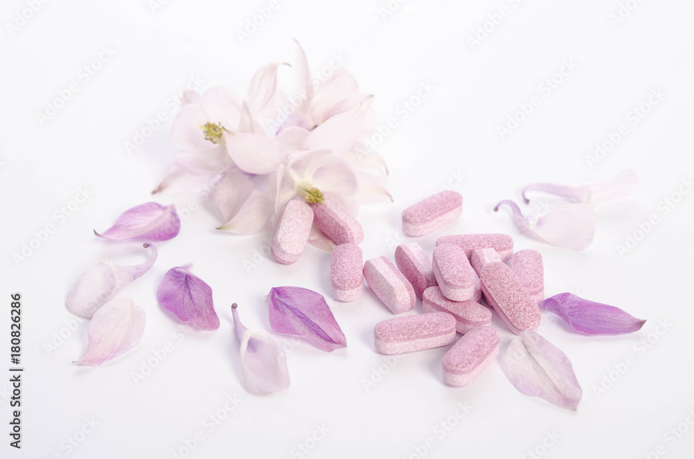 Fototapeta premium Alternative medicine tablets with flowers and petals on table