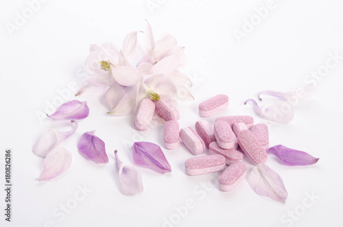Alternative medicine tablets with flowers and petals on table