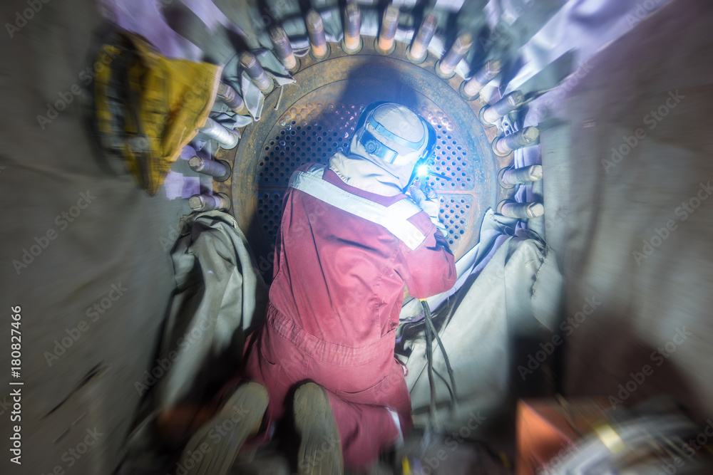 Welder in offshore oil and gas industrial while welding shell and tube heat exchanger to plug and repair tube side of exchange due to extreme corrode and crack at welding joint , Motion blur effect.