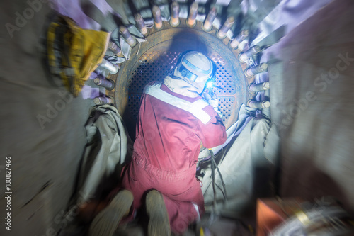 Obraz na płótnie Welder in offshore oil and gas industrial while welding shell and tube heat exchanger to plug and repair tube side of exchange due to extreme corrode and crack at welding joint , Motion blur effect. w salonie