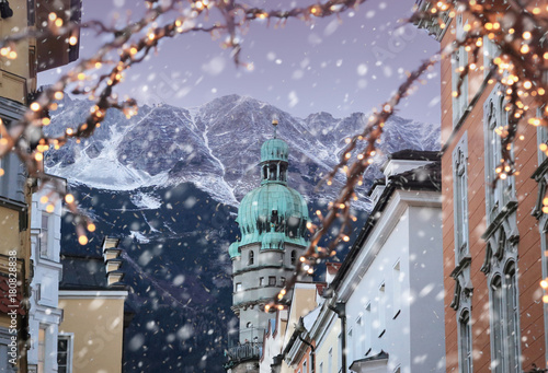 Roofs of Innsbruck with mountains on a background and Christmas lights on a foreground at winter snowy evening photo