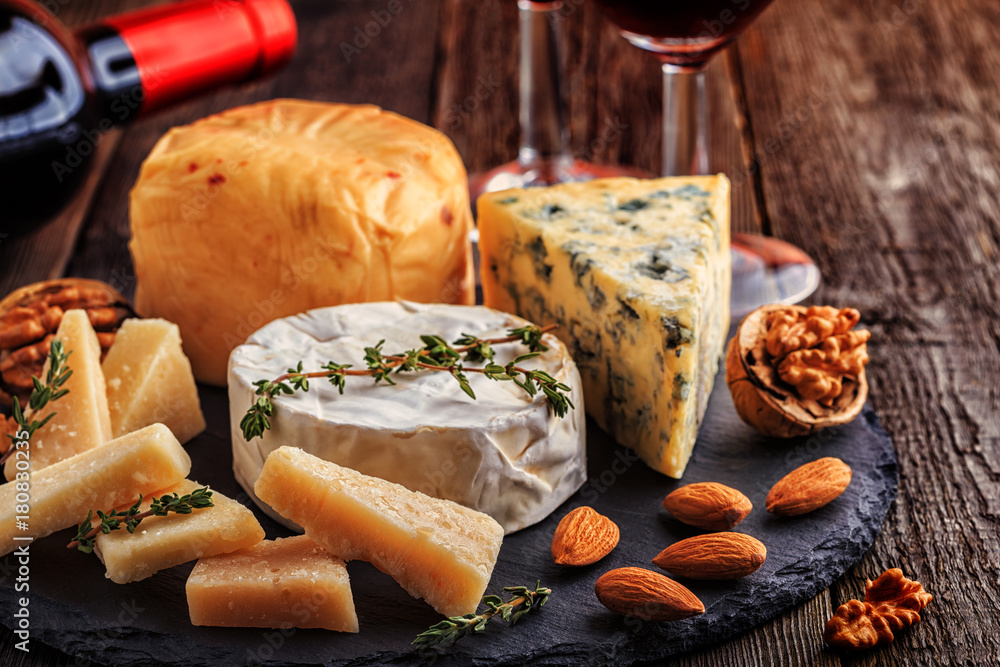Cheese, nuts, honey and red wine on wooden background.