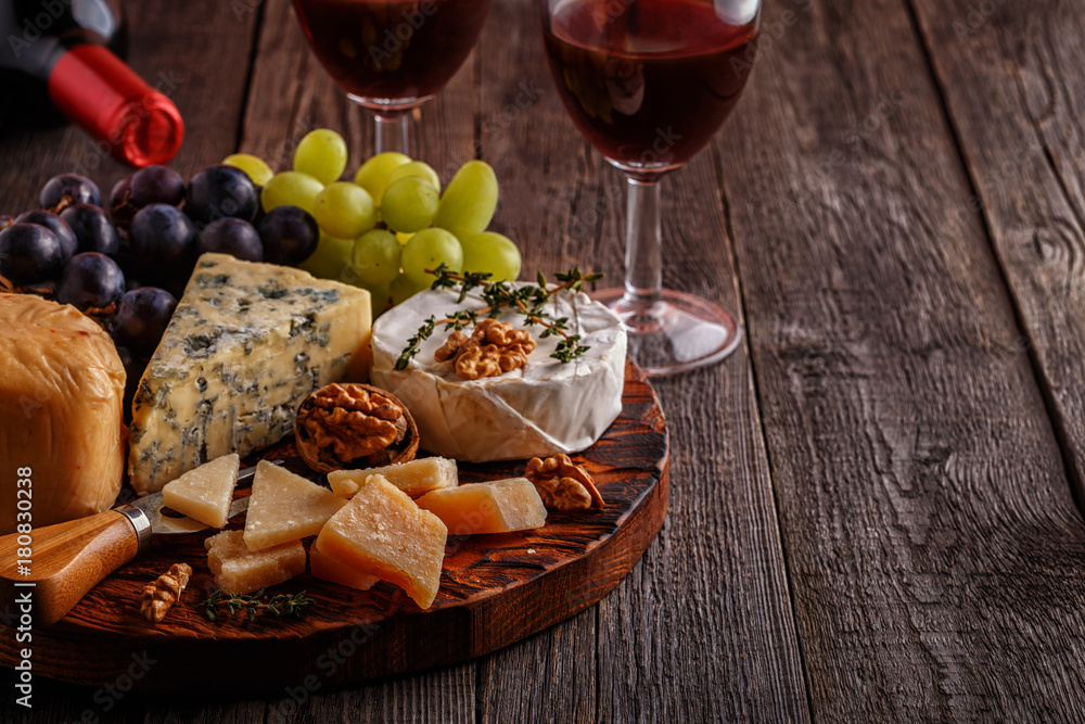 Cheese, nuts, grapes and red wine on wooden background. Cheese, nuts, grapes and red wine on wooden background.