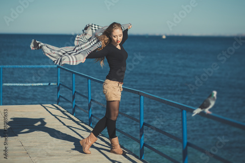 Fototapeta Naklejka Na Ścianę i Meble -  Seductive sexy lady girl with romantic pout red lips and pinky cheeks wearing stylish jacket dress and shorts with autumn boots posing on pier jetty sea side with make up on face i romantic episode