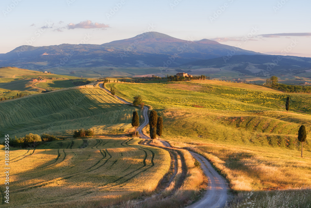 Magnificent spring landscape at sunset.Beautiful view of typical tuscan farm house, green wave hills, cypresses trees, magical sunlight, beautiful golden fields and meadows.Tuscany, Italy, Europe - obrazy, fototapety, plakaty 