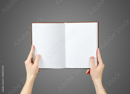 Overhead view of hands holding a blank book ready with copy space ready for text. Isolated on grey background. With clipping path © OB production