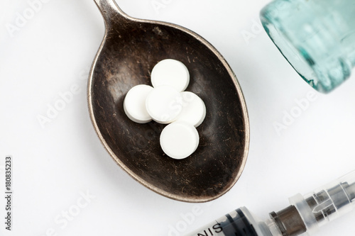 Medications and pills with spoon and syringe on a white background