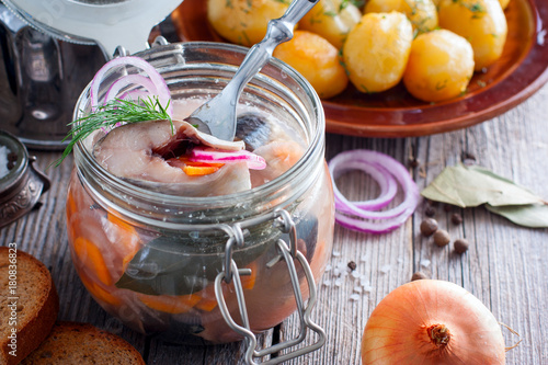 Swedish traditional marinated herring with onions and carrots in a glass jar, selective focus