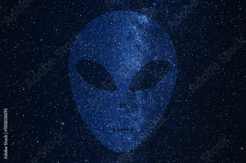 Alien face silhouette on background of Milky Way galaxy with glowing stars and planets in the universe. Space sky in the night.