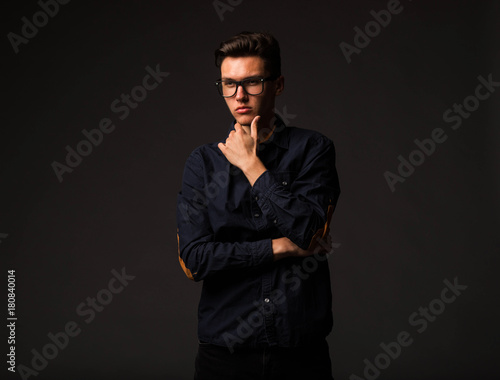 Young pensive man portrait of a confident businessman on a black background. Ideal for banners, registration forms, presentation, landings, presenting concept.