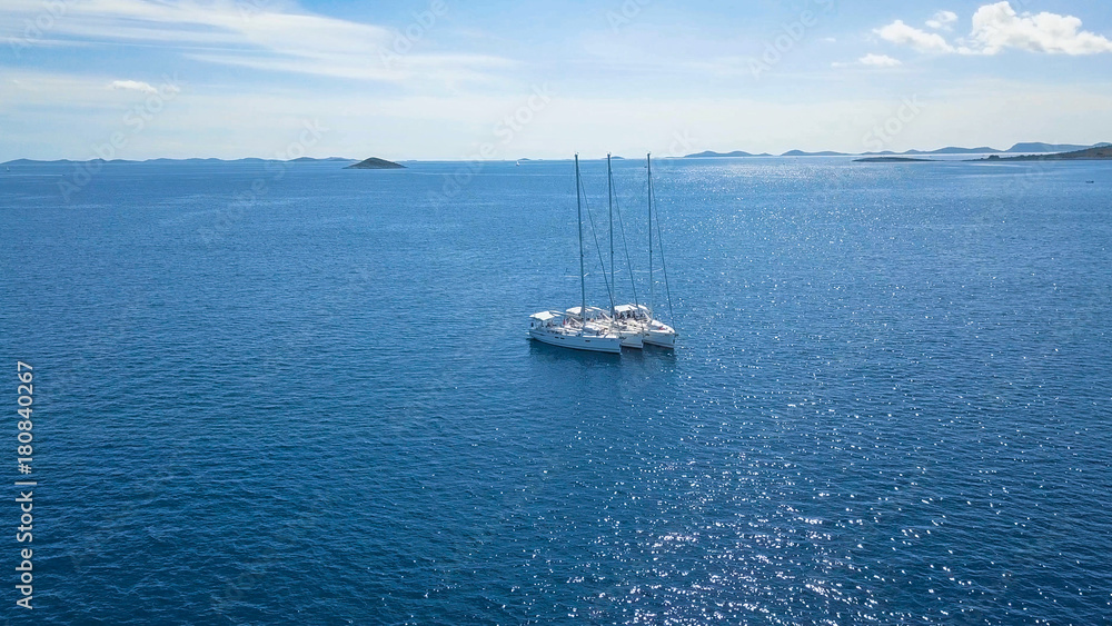 Fototapeta premium Aerial view of yacht sailing near beautiful Islands. Beautiful clouds in the background. Luxury yacht in the sea.