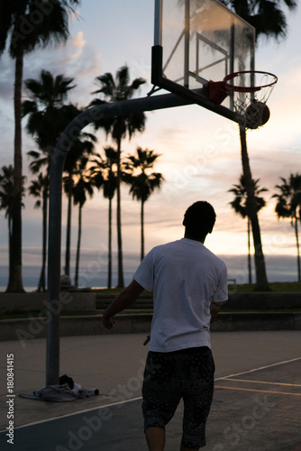 Junger Mann spielt alleine im Sonnenuntergang Basketball auf dem Venice Beach Court © Stefan