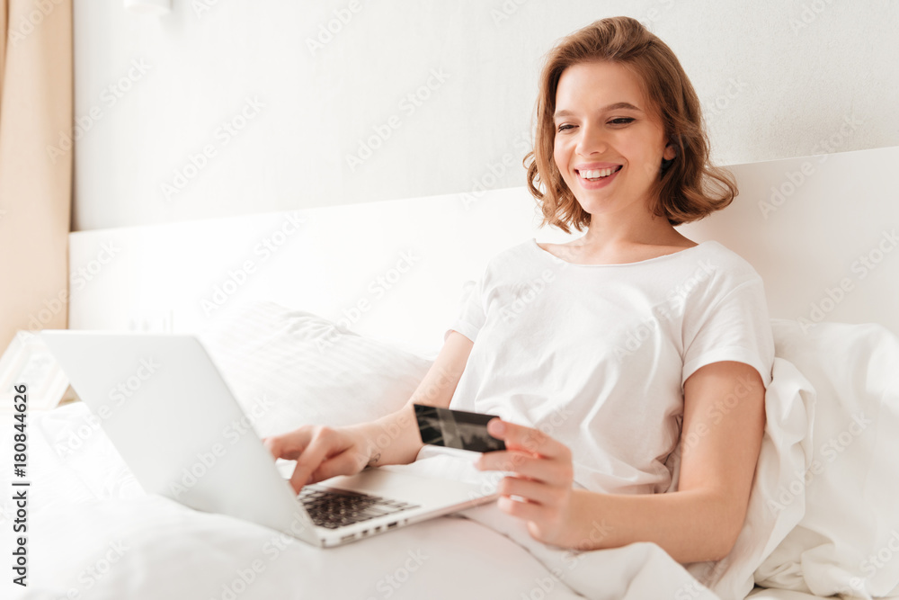 Happy young amazing woman sitting indoors using laptop Happy young amazing woman sitting indoors using laptop