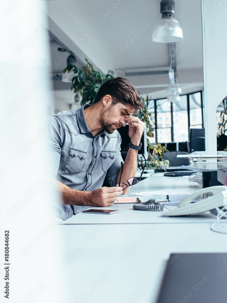 Tired young businessman in the office - obrazy, fototapety, plakaty 