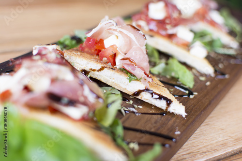 Baguette slices, camembert cheese, and spices on wooden background. Sausage and prosciutto slices on a wooden board. Appetizers served at an event.
 photo