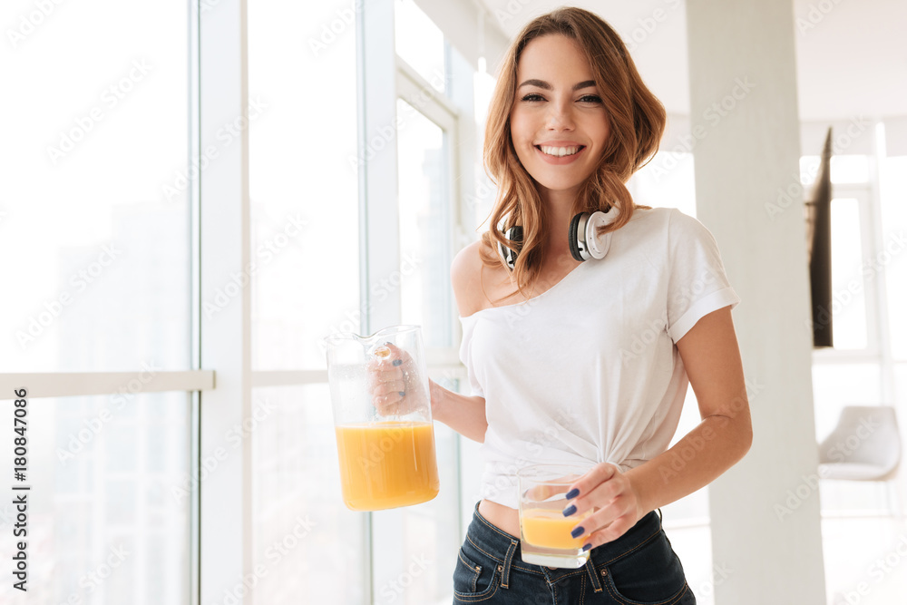 Happy young lady with headphones drinking juice Happy young lady with headphones drinking juice