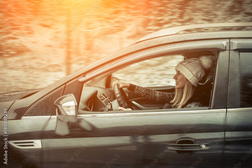 Woman at winter time. Yoyng female sitting and driving in black
