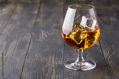 glass of whiskey with ice on a wooden background © Andrey Cherkasov